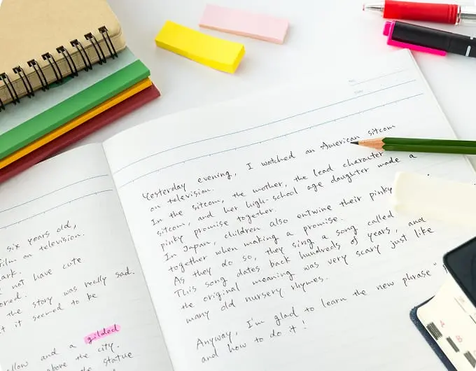 机にノートや付箋を広げながら英語対策をしているイメージ