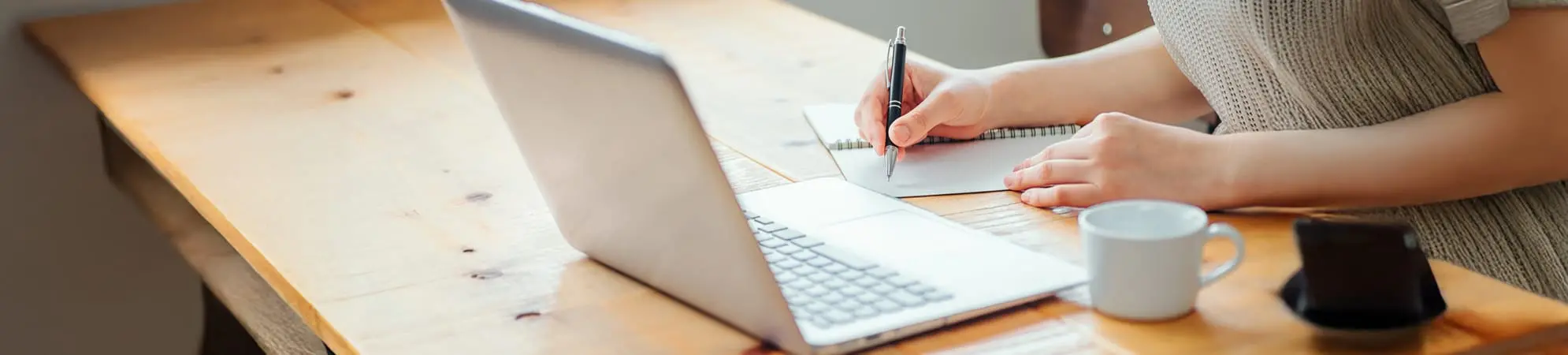 保護者が机の上でPCとノートで作業をしている様子