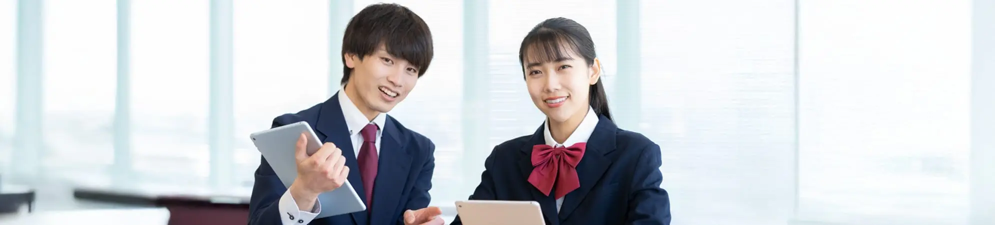 中学生の男女がタブレットで勉強しています