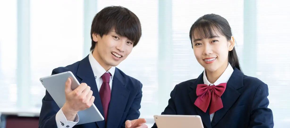 中学生の男女がタブレットで勉強しています
